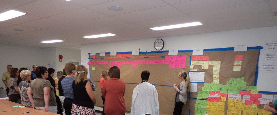 Workshop participants reviewing a large wall of improvement notes.